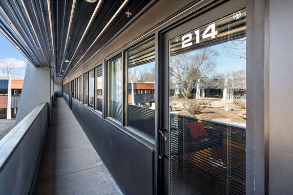 View from a corridor with glass windows overlooking exterior areas and adjacent buildings.