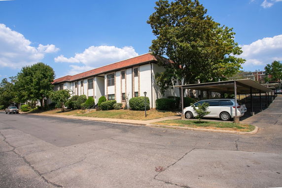 Front view of a multi-story residential building with a covered parking area.