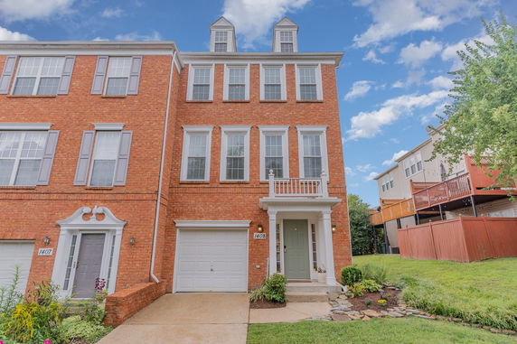 Front view of a three-story brick townhouse with a single garage.