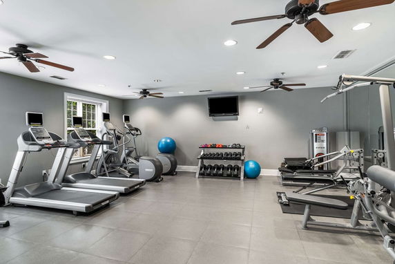 Indoor gym area with treadmills, exercise machines, dumbbells, and fitness equipment.