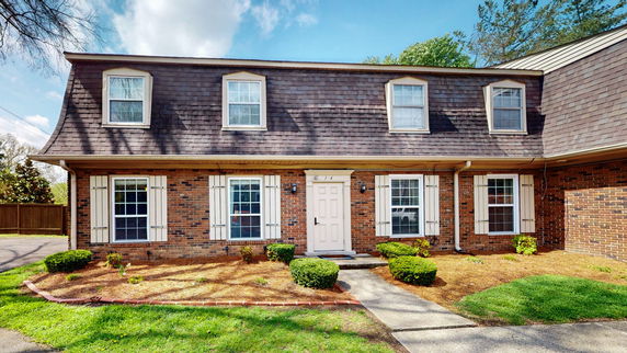 Front view of a two-story brick house with multiple windows and a gable roof.