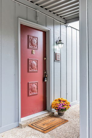 Front view of a house entrance with a red door and decorative panels.