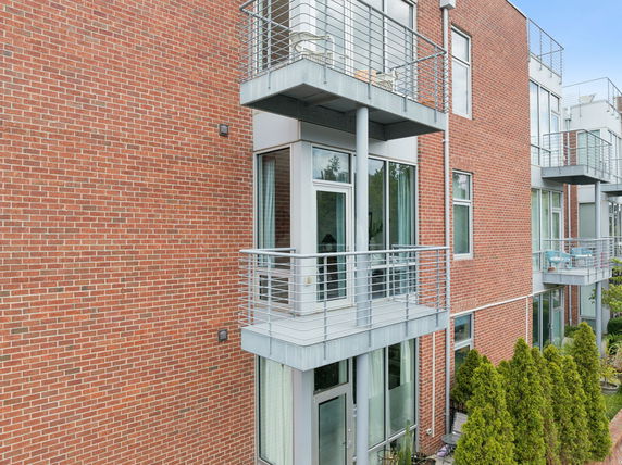 Side view of a multi-story building with balconies and brick exterior.
