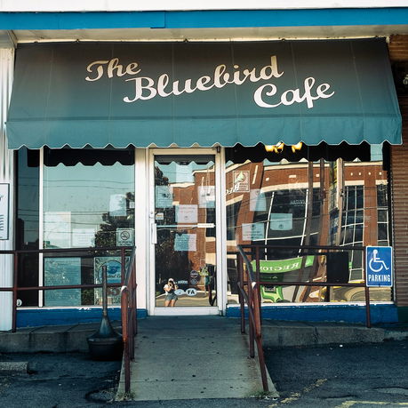 Front view of a cafe with an awning displaying 'The Bluebird Cafe'.