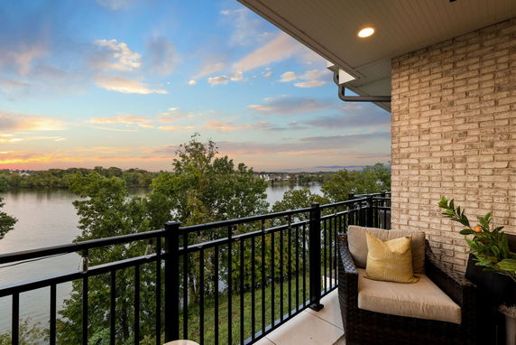 Balcony view overlooking a serene river and lush greenery at sunset.