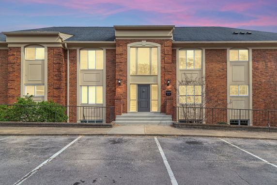 Front view of a two-story brick building with large windows and a central entrance.