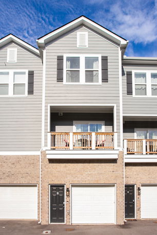Front view of a multi-story house with garages and balconies.