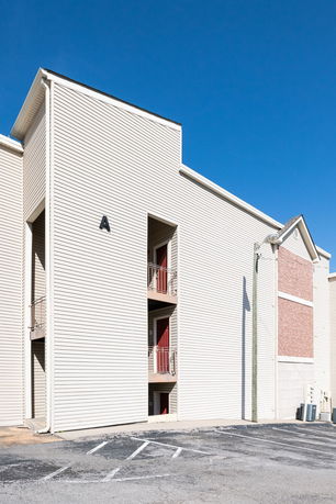 Front view of a building with beige siding and red doors.