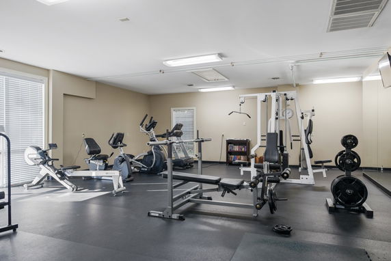 Gym area with exercise equipment including bikes and weights.