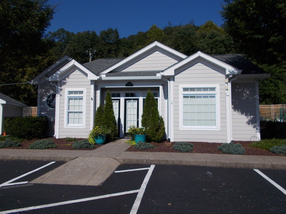 Front view of a small single-story structure with white siding and a gabled roof.