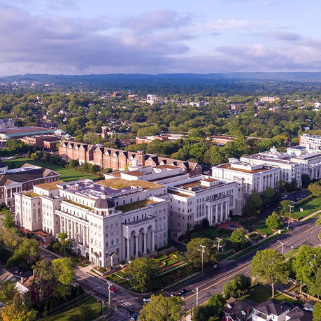 Aerial view of a large institutional complex with surrounding greenery and roads.