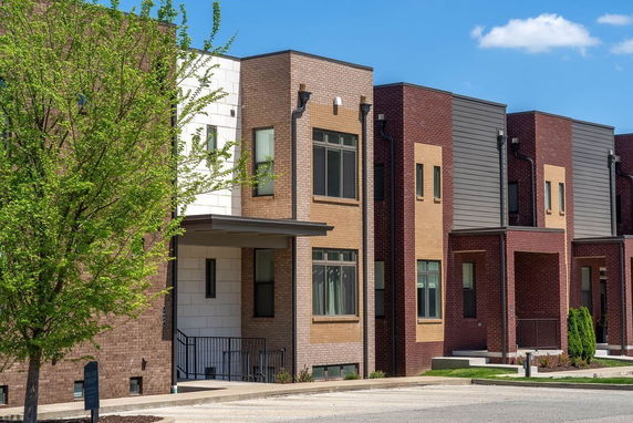 Front view of a row of modern townhouses with brick and siding exteriors.