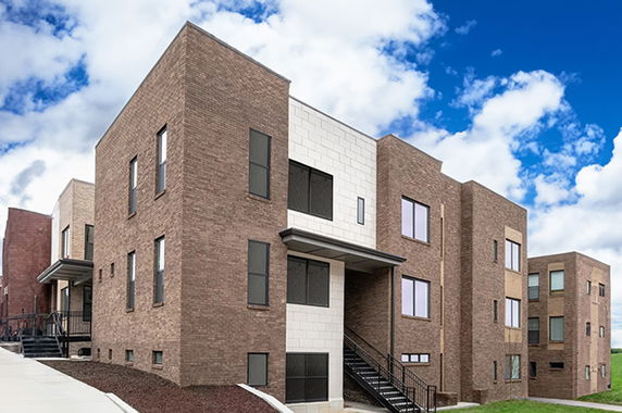 Front view of a modern multi-story brick building with multiple windows and exterior stairs.