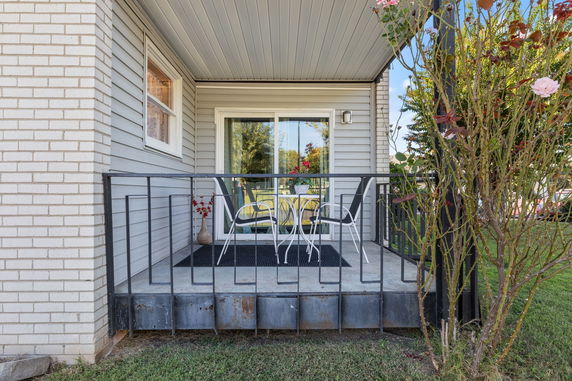 Front view of a house with a small patio and metal railing.