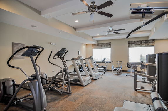 Room with gym equipment including treadmills and exercise machines.