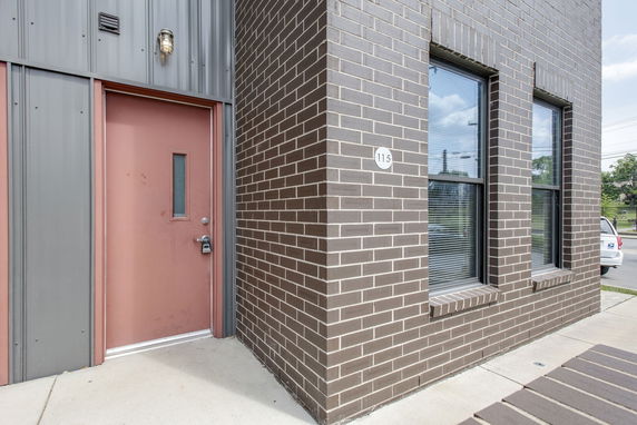 Front view of a building with brick exterior and a reddish-brown door.