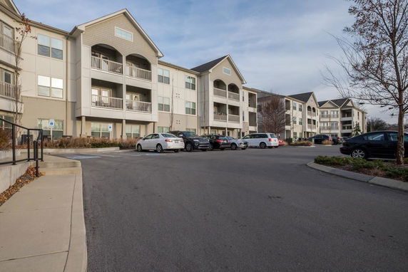 Parking area in front of a multi-story apartment building with balconies.
