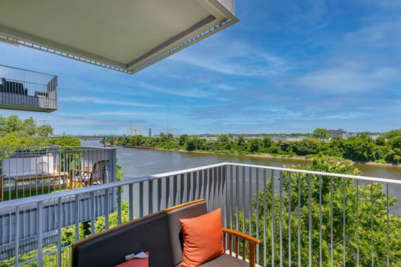 Panoramic view from a balcony overlooking a river and greenery.