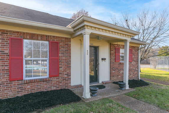 Front view of a single-story house with brick exterior and red shutters.