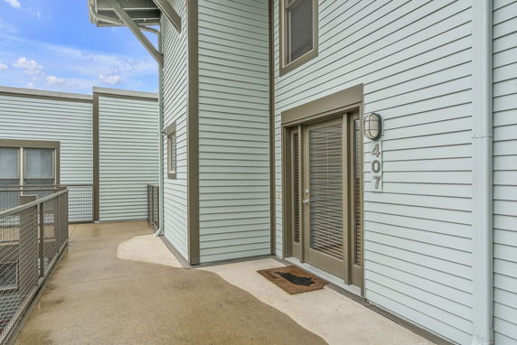 Exterior view of a building with a light-colored siding and door marked 407.