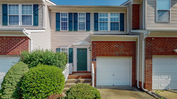 Front view of a two-story townhouse with a green door and attached garage.