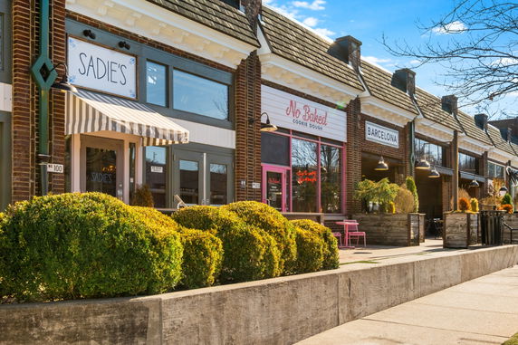 Front view of a row of storefronts with signage and awnings.