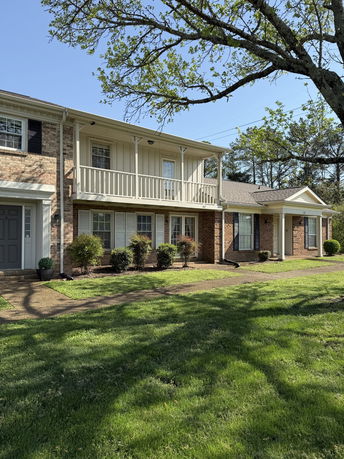 Front view of a two-story house with a balcony and brick exterior.