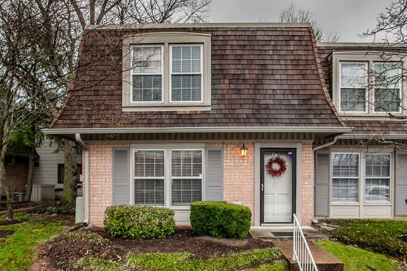 Front view of a house with brown shingled roof and brick exterior.