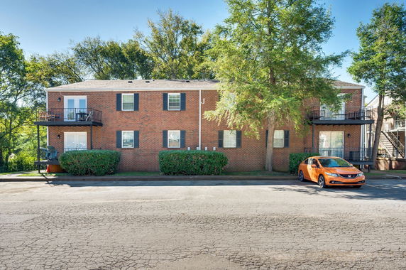 Front view of a two-story red brick apartment building with exterior balconies.