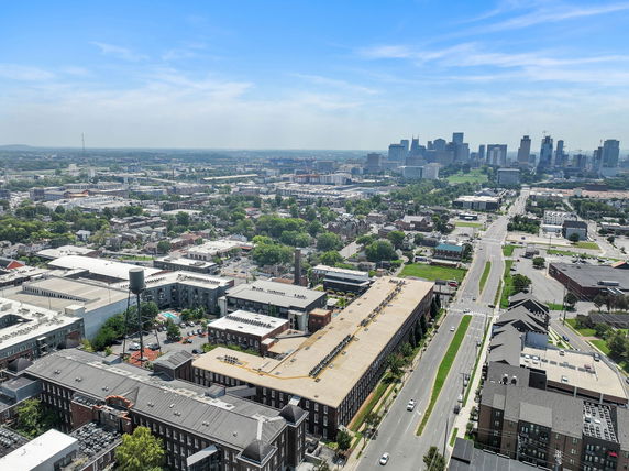 Panoramic aerial view of a cityscape with roads, buildings, and distant skyline.