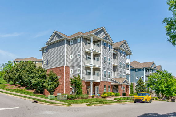 Front view of a multi-story apartment building with balconies and mixed brick and siding exterior.