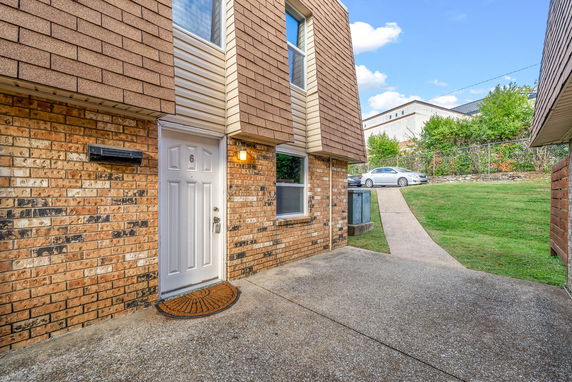 Front view of a brick house with a white door and shingle siding.