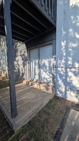 Front view of a building with sliding glass door and a small concrete porch.