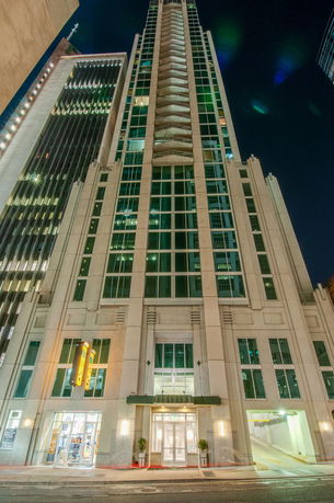 Front view of a tall modern building with a glass façade at night.