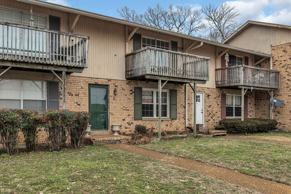 Front view of two-story brick building with balconies and multiple entrances.