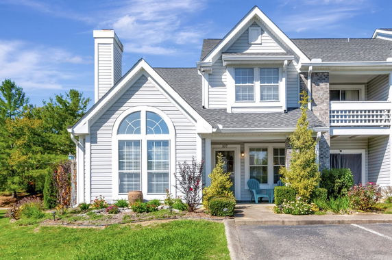 Front view of a house with a prominent arched window and porch seating area.