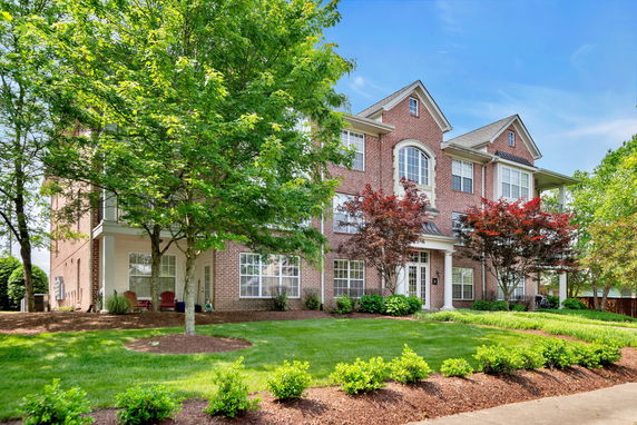 Front view of a multi-story brick house with large windows and a prominent entrance.