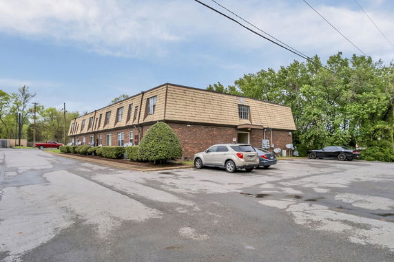 Front view of a two-story brick building with a shingled roof and parking area.