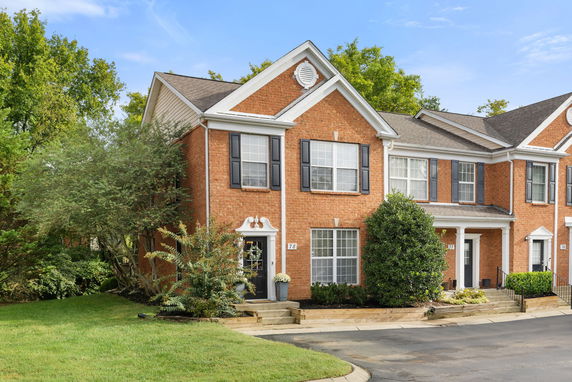 Front view of a two-story brick townhouse with white trim and black shutters.