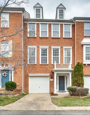 Front view of a three-story brick townhouse with a garage and central entrance.