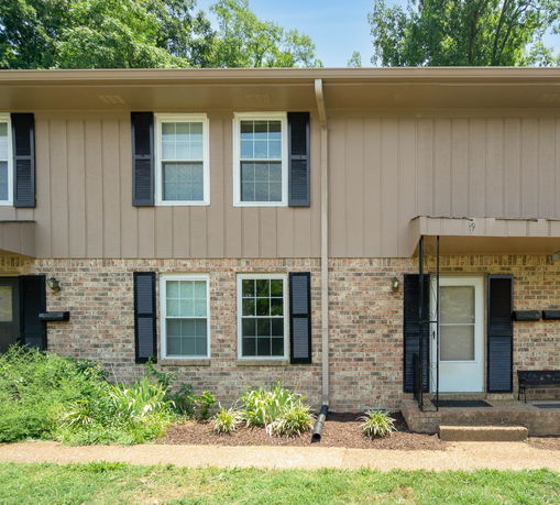 Front view of a two-story house with brick facade and black shutters.