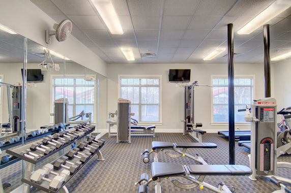 Interior view of a gym area with exercise equipment and mirrors.