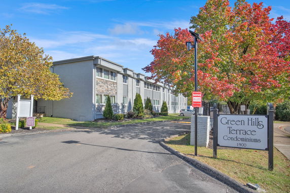 Front view of a multi-story condominium building with a sign for Green Hills Terrace.