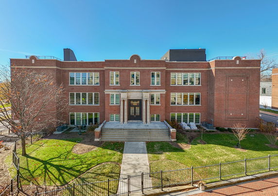 Front view of a three-story brick building with multiple windows and a central entrance with columns.