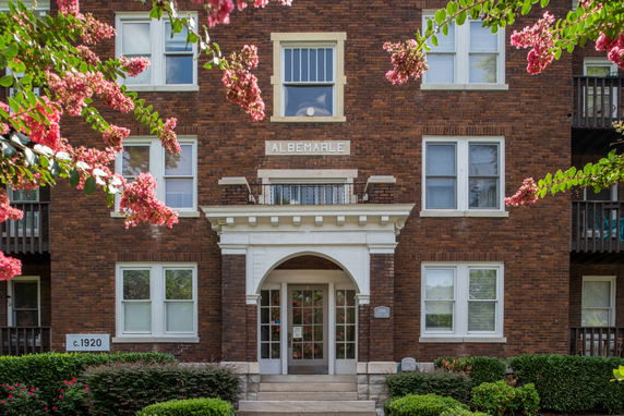 Front view of a multi-story brick building with symmetrical windows and an arched entrance.