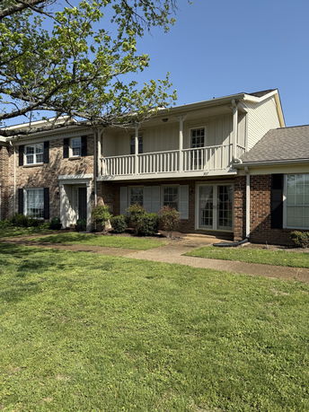 Front view of a two-story brick house with a balcony.