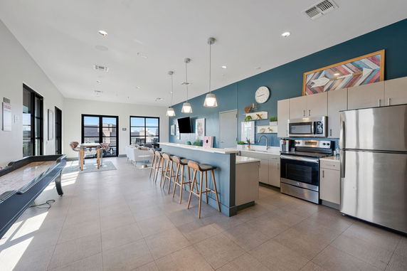 Recreational room with kitchen area, bar seating, sofa, and table games.