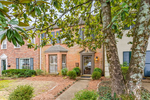 Front view of a two-story brick house with shutters and a prominent entrance.