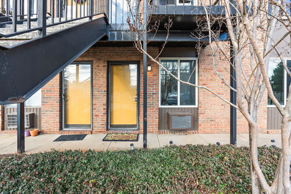 Front view of a brick building with yellow doors and external stairs.