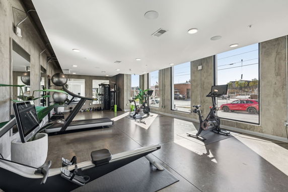 Indoor gym area with exercise equipment and large windows.